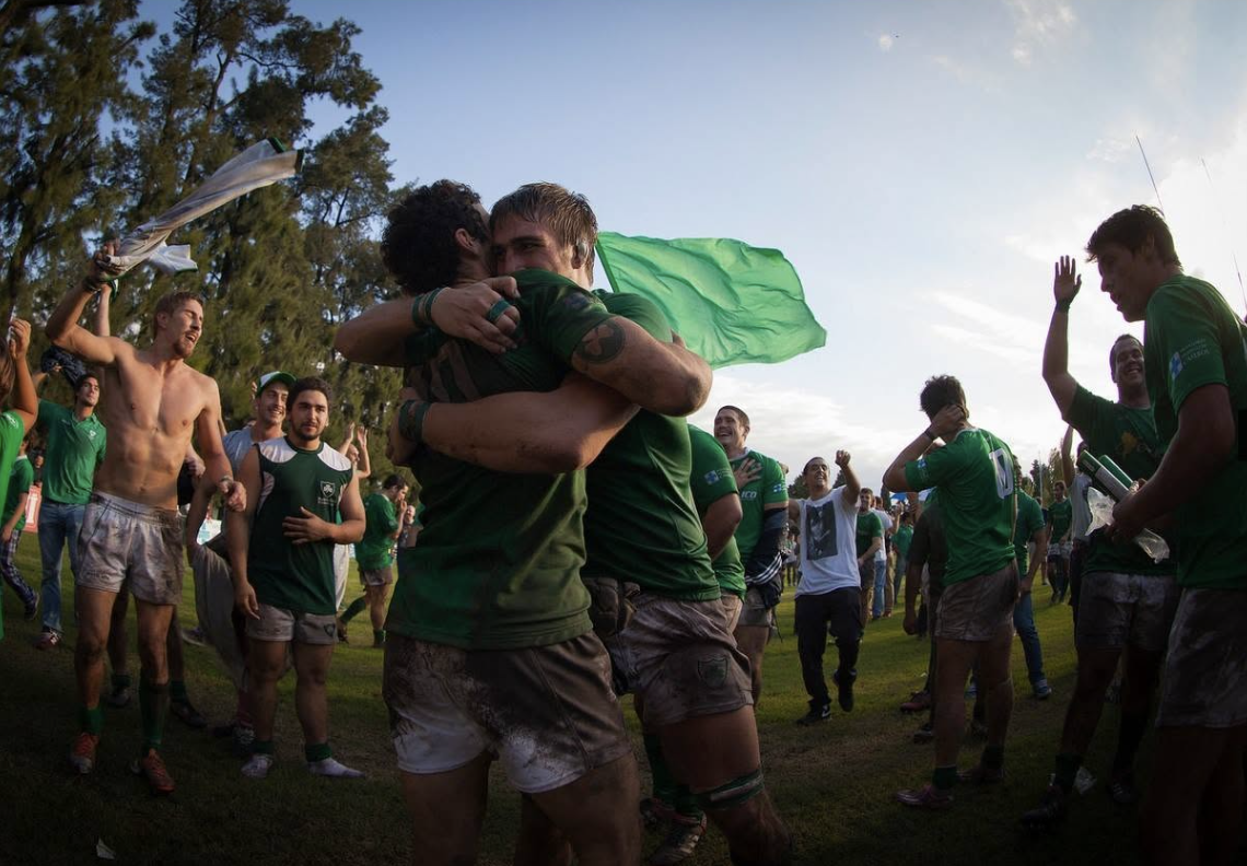 Los jugadores del Hurling Club se abrazan y festejan con la bandera verde tras el ascenso.